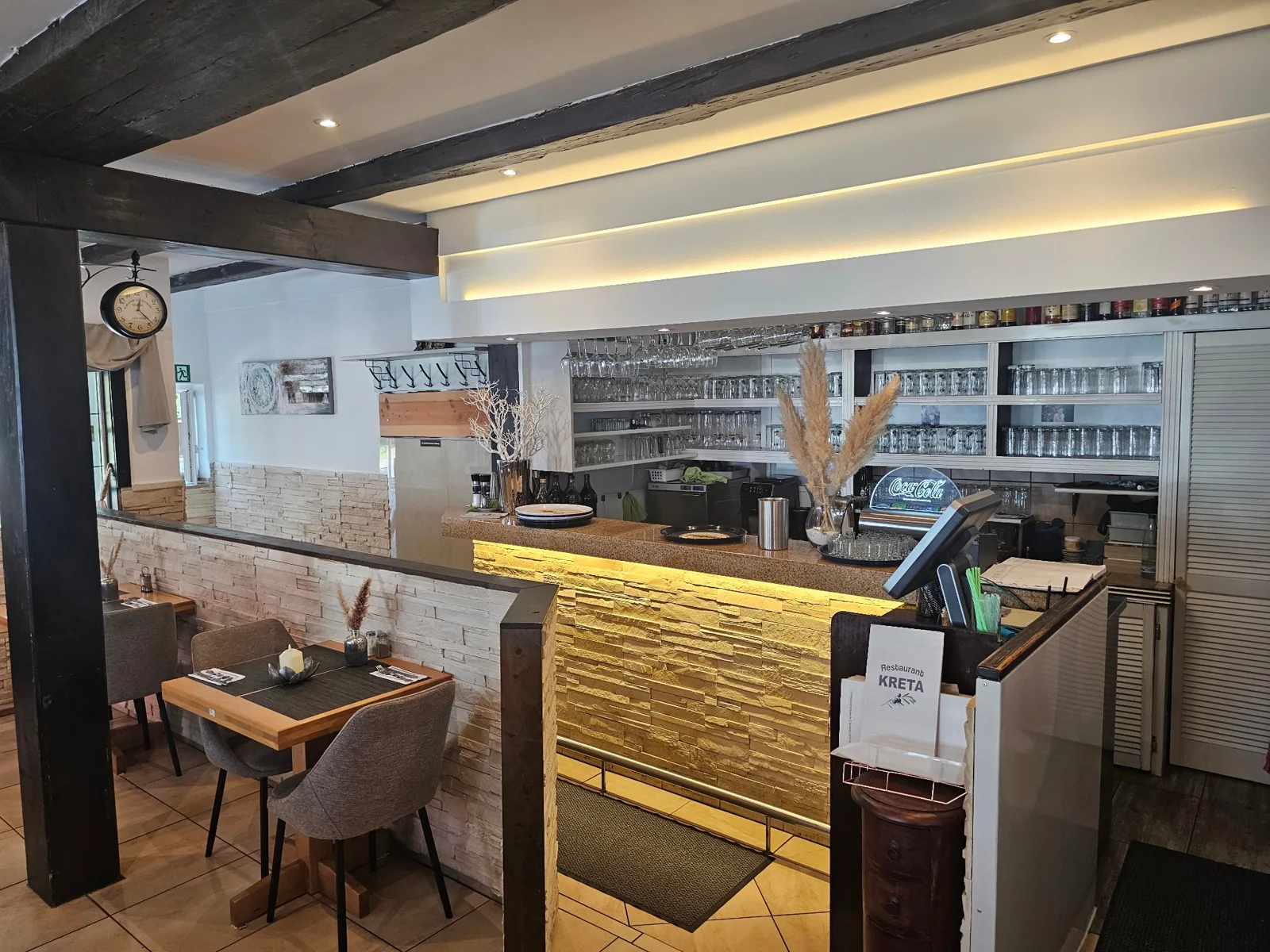 Beleuchtete Theke mit Steinverkleidung und Gläserregalen im Restaurant Kreta