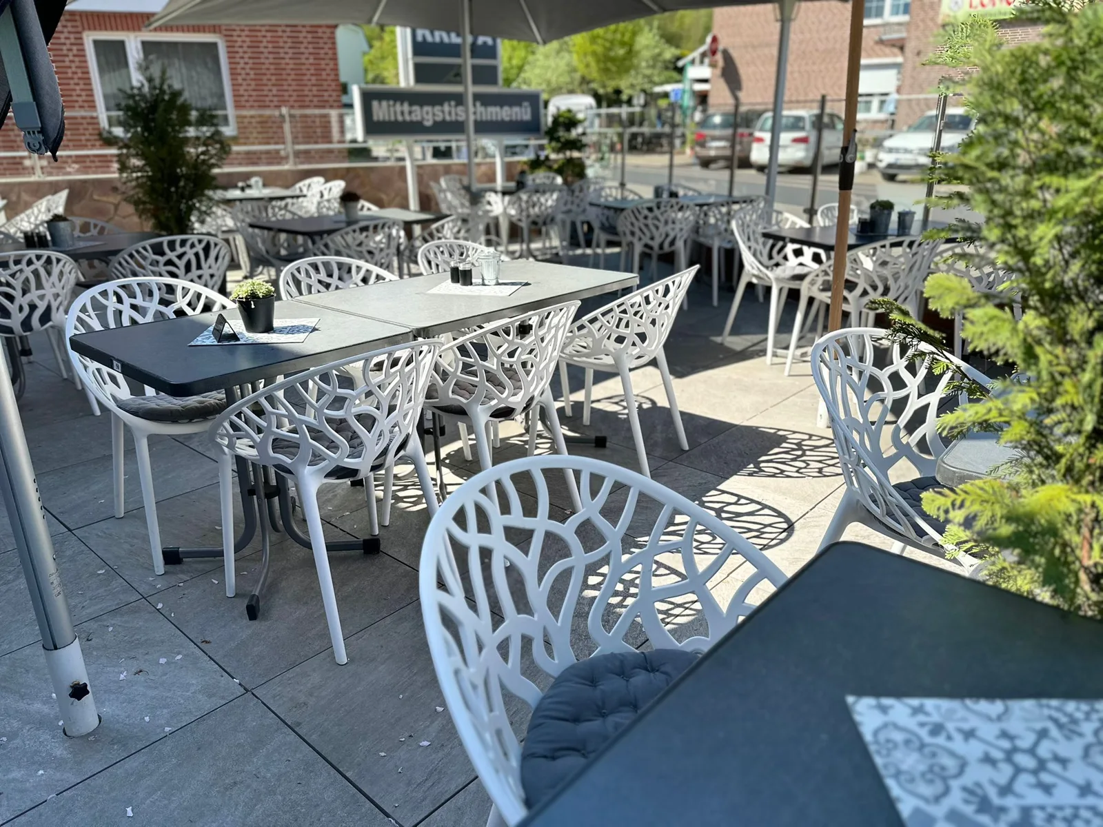 Terrasse von Restaurant Kreta in Grömitz mit weißen Stühlen und Sonnenschirmen